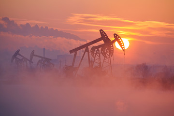 The oil pumping units by lakeside sunrise.