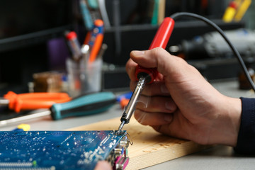 computer service worker holding soldering iron close up