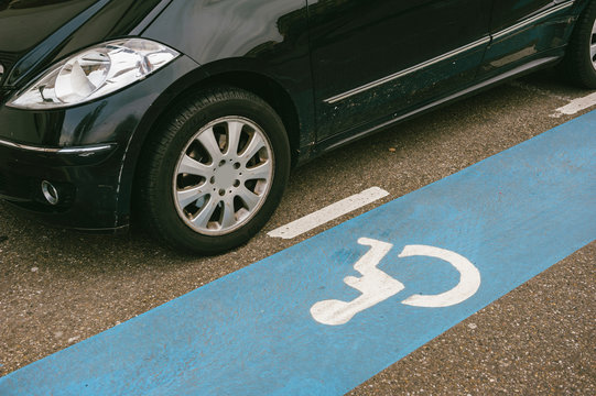 Strasbourg, France - Dec 28, 2012: Car detail near dedicated blue stripe for disabled parking spaces with white pictogram painted on an asphalt