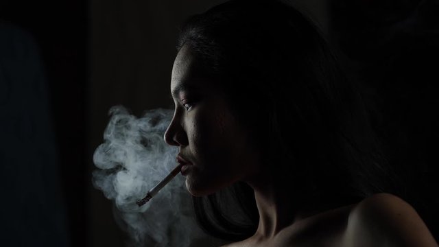 Asian woman inhaling and cigarette vaping. Female secretly smoking in bathroom at home. Concept of quit smoking and anti cigarette.