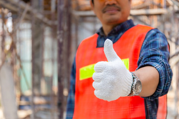 Engineer / worker man hand giving thumb up over blurred construction site, Successful concept