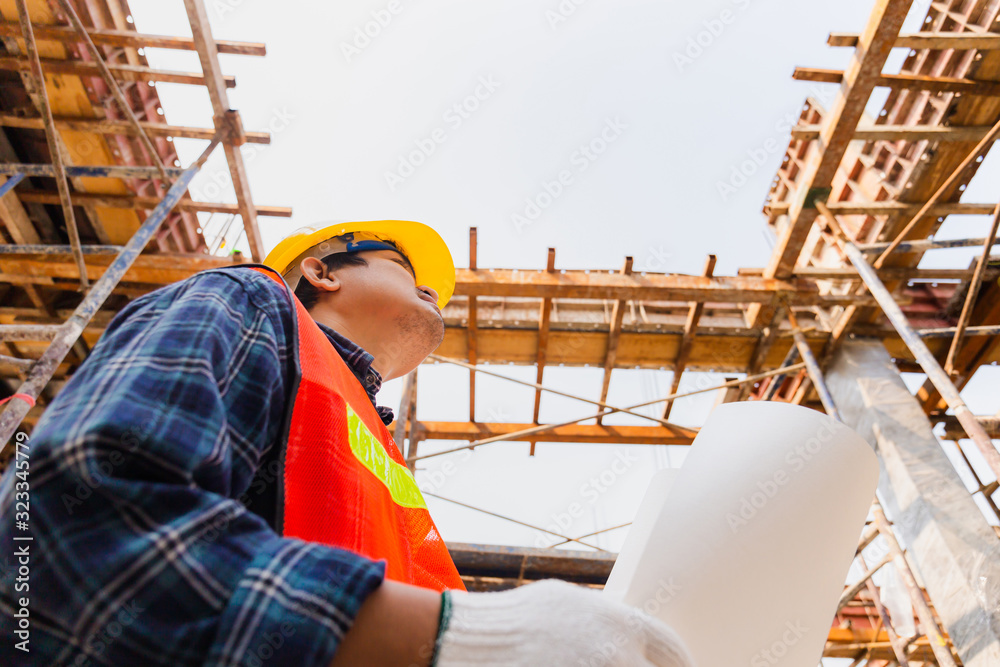 Wall mural engineer / worker man holding blueprint checking and planning project at construction site