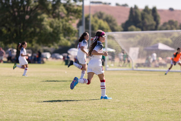 A girl with sports goggles is playing competitive soccer.