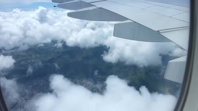Picturesque aerial view from airplane window on air plane wing flying high over white fluffy clouds in clear blue sky