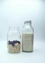 Mason Jar with oats and blueberries, next to Milk bottle