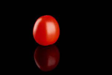 One red tomato on a black glossy background