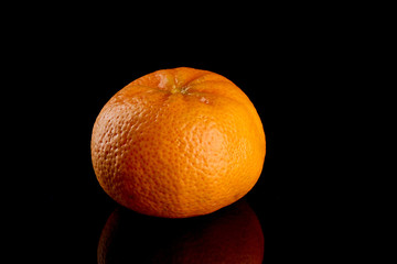 one tangerine fruit on a black glossy background