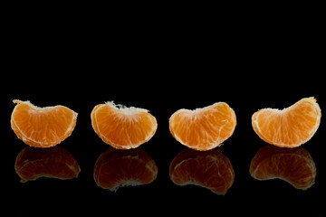peeled slices of juicy, ripe mandarin on a black background