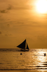 Fototapeta na wymiar フィリピン、ボラカイ島のオレンジ色の夕焼けと海と人とヨットのシルエット