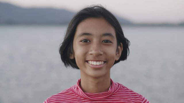 Medium close up of asian little girl smile and happy enjoying nature on beach at sunset. Close up of asia girl on face expression.  relaxation lifestyle concept