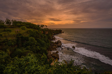 Fototapeta premium Balinese coast, green forest, hanging cliff and rocky beach, Bali Indonesia