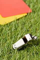 Soccer sports referee yellow and red cards with chrome whistle on grass background selective focus