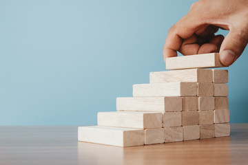 Business concept of ladder career path and growth success process. Hands of men arranging wood cube block stacking as step stair.