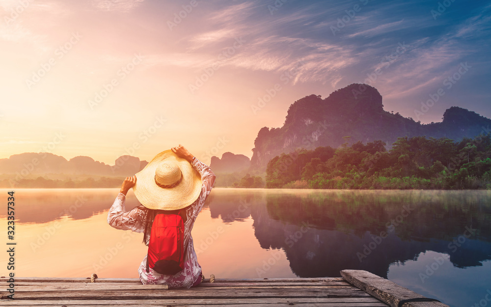 Wall mural traveler woman joy looking beautiful sunrise view reflection nature mountain landscape on lake, life