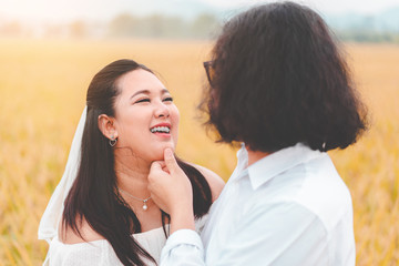 Lovely couple Groom touch her chin bride at meadow outdoor location, selective focus.