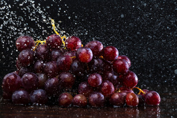 Grapes in spray of water close-up on a black background