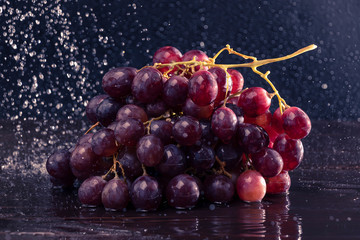Grapes in spray of water close-up on a black background