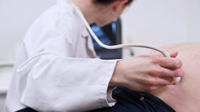 Doctor checks pregnant woman with ultrasound .
