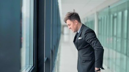 Closeup, handsome man in business suit standing at window aggressively knocking and angry