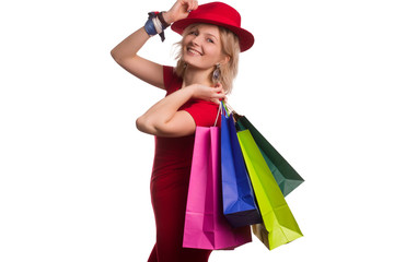 blonde girl with short hair on isolat in a red dress and a red hat, with colored paper shopping bags. The concept of shopping or sales,