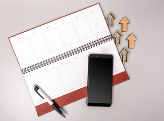 An open notebook in leather binding with a smartphone and pen on a gray background. Business growth...