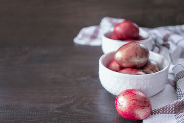 pink Easter eggs in white bowls on the table close-up. Easter background with painted pink eggs.