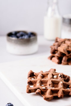 Homemade Chocolate waffles, milk and blueberries on white marble tray. Breakfast. Selective focus