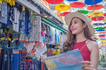 Smiling woman traveler in chiangmai market landmark thailand holding world map on holiday, relaxation concept, travel concept