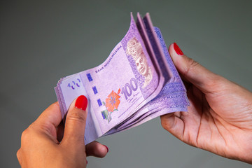 Female Hands with red nails counting 100 Ringgit banknotes. Ringgit the currency of Malaysia. Woman hands showing RM100 notes. Close up to the Malaysian money with colorful fingernails 