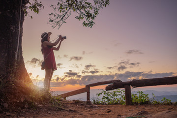 Smiling woman traveler in mountains at sunset and enjoying view of nature chiangmai landmark in thailand holding camera with backpack in holiday, relaxation concept, travel concept