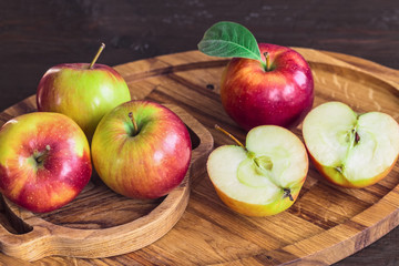 red apples on a wooden tray close-up. background with ripe apples and apple halves.