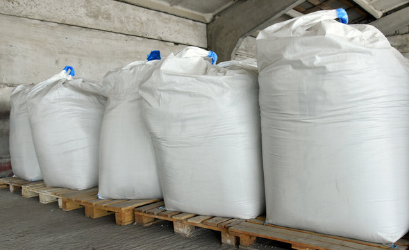 Large bags of grain on wooden pallets, warehouse.