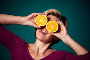 Happy woman holding orange near face. People, lifestyle and health concept