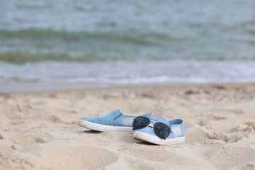 Obraz premium sneakers and sunglasses on the sea