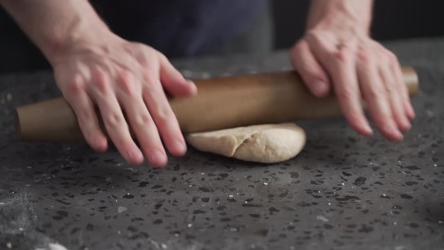 man rolling dough on concretre countertop