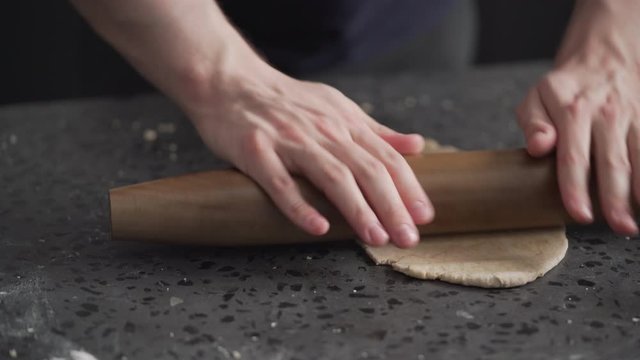man rolling dough on concretre countertop