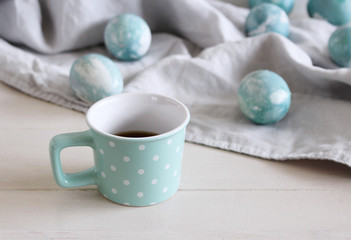 Spring breakfast still life scene. Mug with coffee, Easter eggs on linen tablecloth. Easter food and drink concept. Farmhouse table