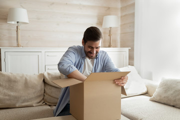 Excited male client unpack internet delivery package