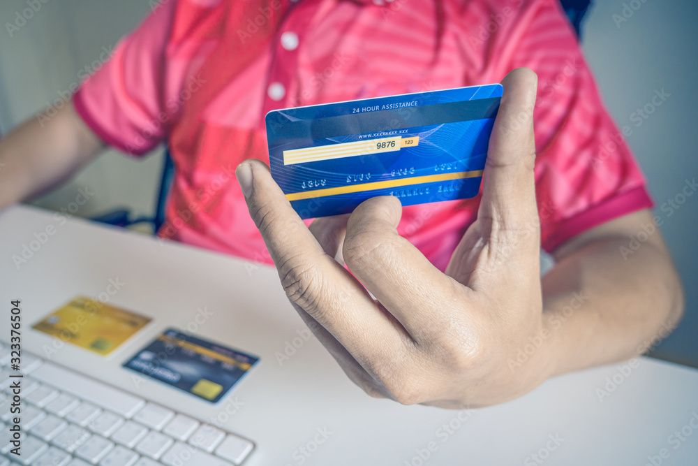 Poster man paying with credit cards on computer at home.