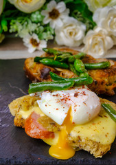 Breakfast on a black slate blackboard. Croutons with cheese, sausage, poached egg, green green beans.