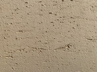 Beige decorative stucco on uneven wall surface painted during apartment renovation. Repair and decoration of premises. Background texture pattern copy space for text