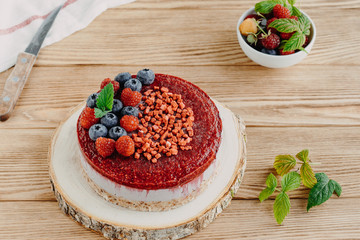 Raw dessert. Cake with berries and nuts, on a wooden background