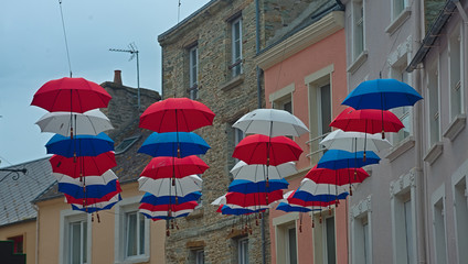 Many hanging umbrellas between street buildings