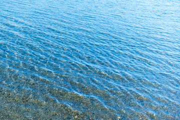 Sea blue water surface with waves near the shore. Background texture.