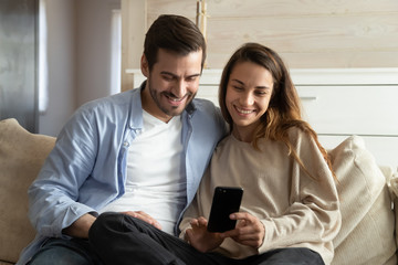 Happy young man and woman relax at home using cellphone