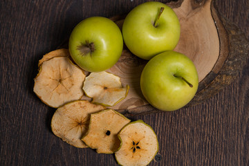 Dried apples  near three fresh on a wooden background.