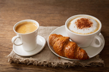 cup of cappuccino with croissant and cup of coffee