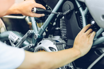 Bike repair. Young man repairing  motobike in garage.mechanic fixing motocycle engine.Serious young man repairing his motorcycle in bike repair shop.