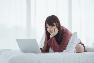 woman working on a laptop sitting on the bed in the house.