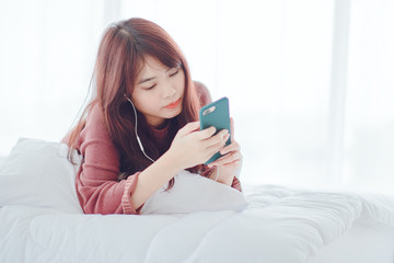 A woman playing on the phone in the bed in the house